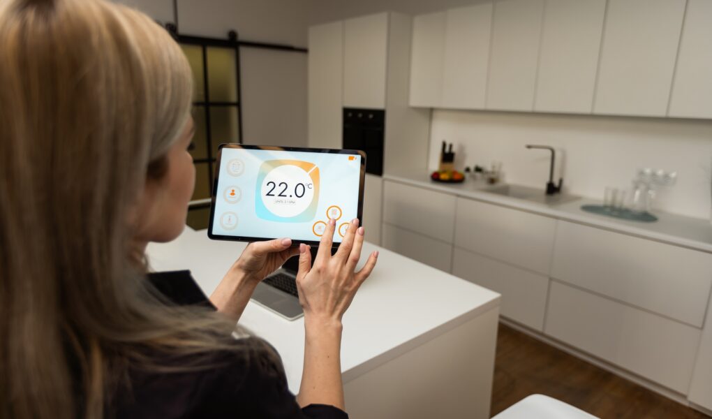 Iot Smart Home Concept - rear view of woman ask digital tablet to set temperature of air conditioner