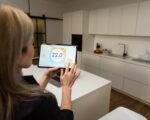 Iot Smart Home Concept - rear view of woman ask digital tablet to set temperature of air conditioner